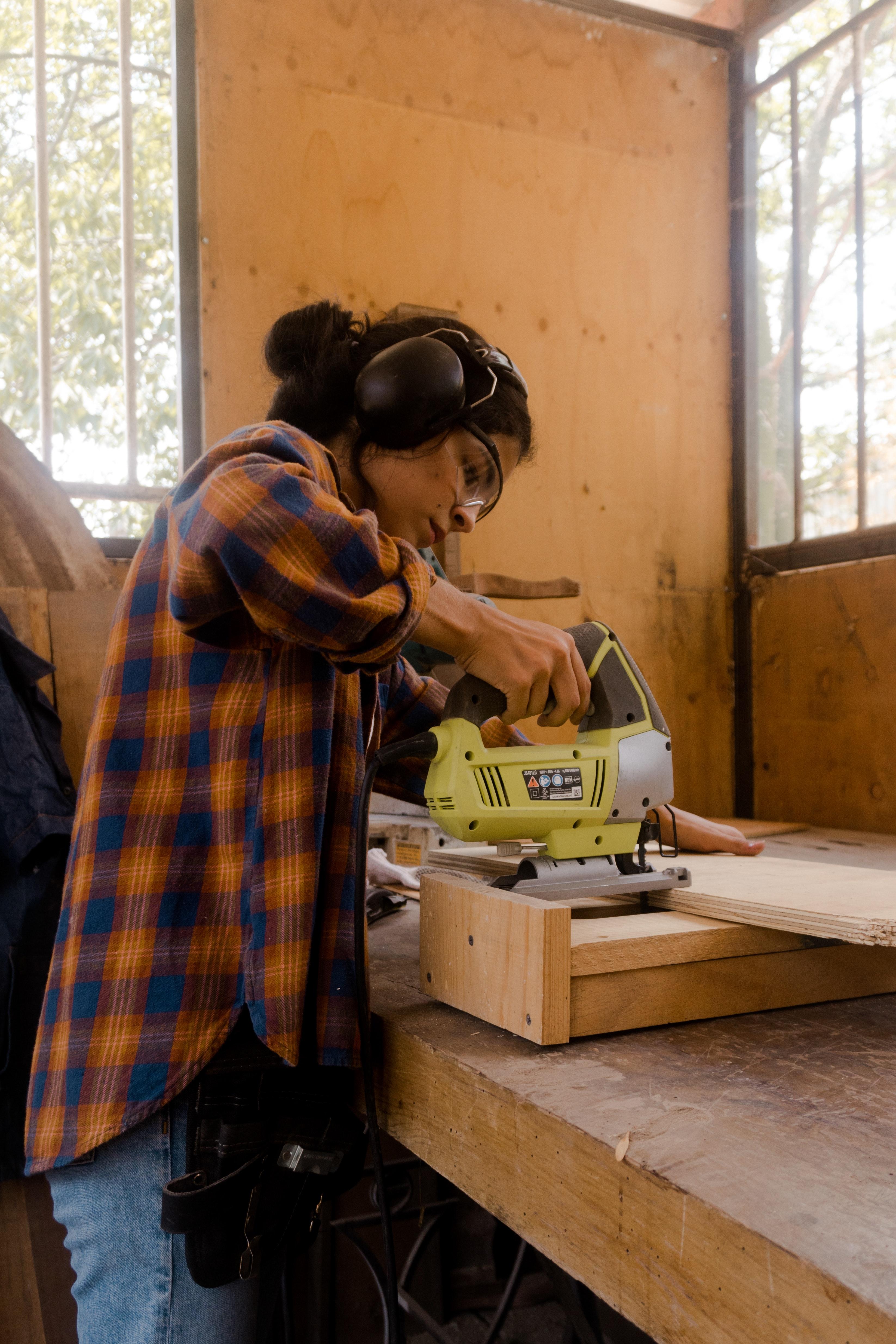 Person using a jigsaw power tool to cut wood.
